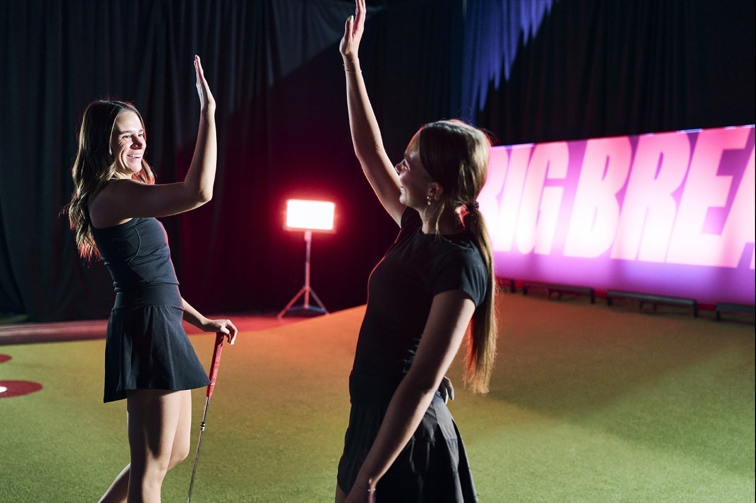 Two teammates high-five on the arena green