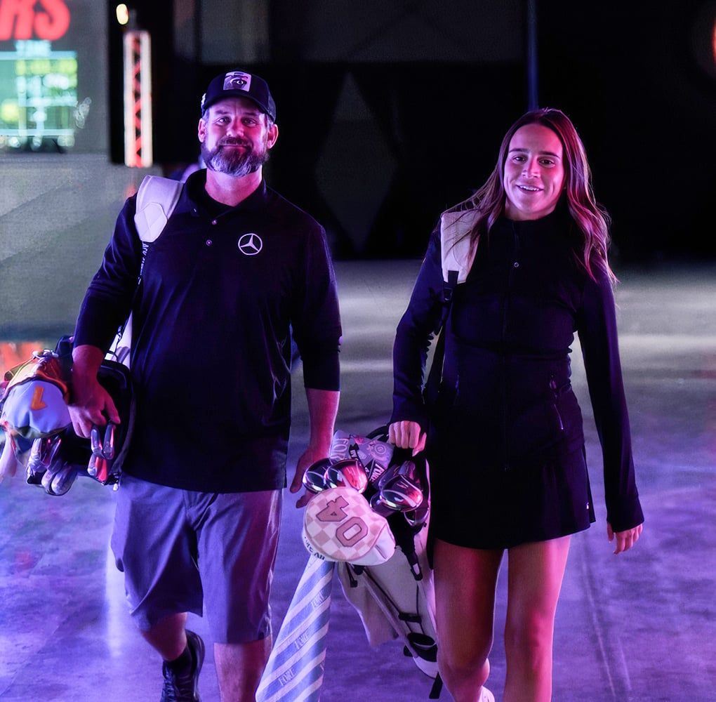 Two golfers walking through the arena with their bags