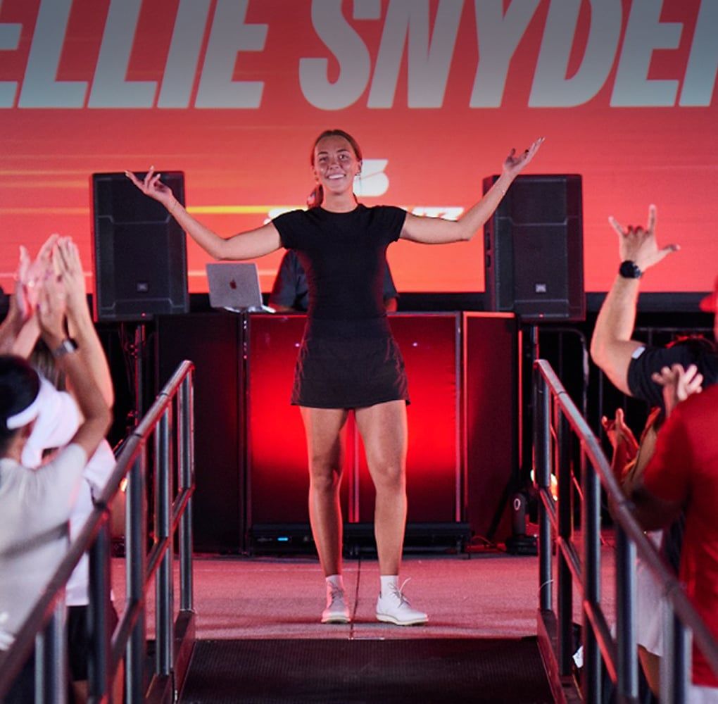 A golfer celebrating on a lit stage in the arena